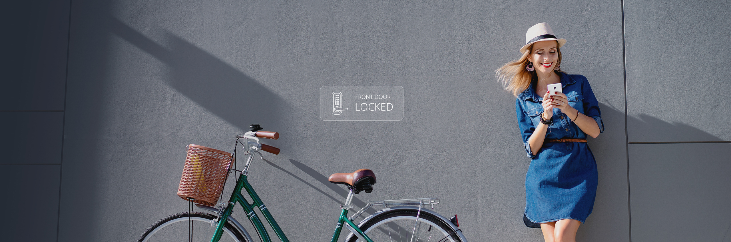 Woman Leaning on Grey Wall Holding Phone with Bicycle Beside Her. Caption Says Front Door Locked – Toronto Vancouver